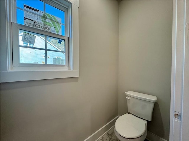 bathroom with marble finish floor, toilet, and baseboards