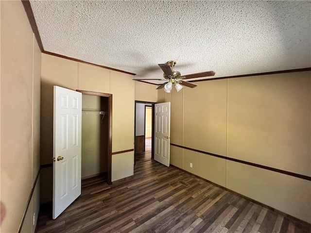 unfurnished bedroom with ceiling fan, dark hardwood / wood-style floors, crown molding, a textured ceiling, and a closet