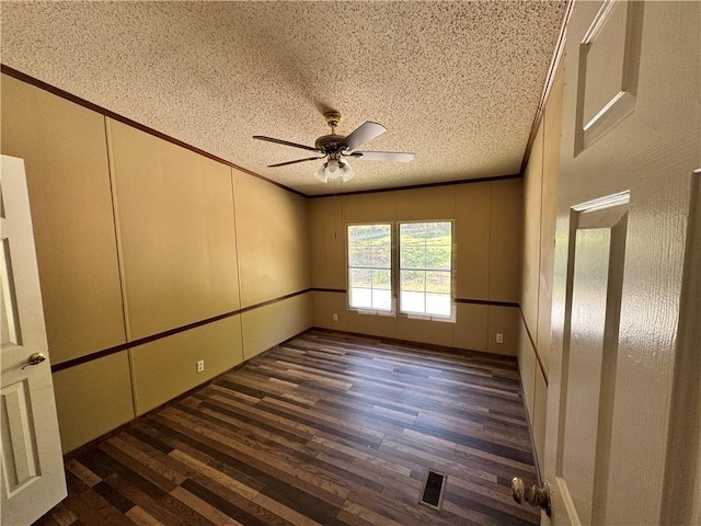 spare room featuring ceiling fan, dark wood-type flooring, a textured ceiling, and ornamental molding