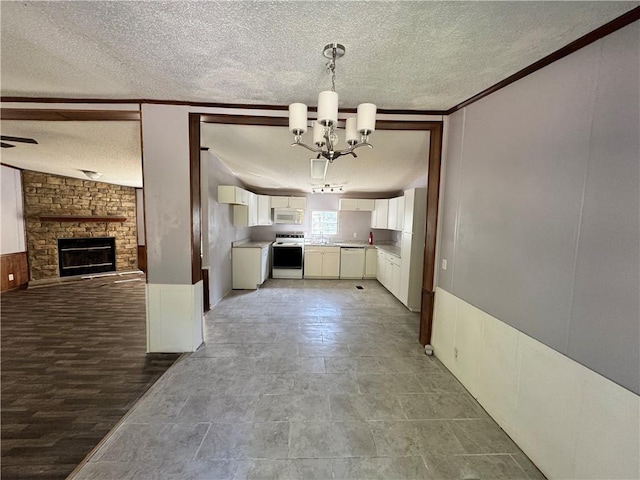 kitchen featuring a notable chandelier, white appliances, white cabinets, a fireplace, and decorative light fixtures