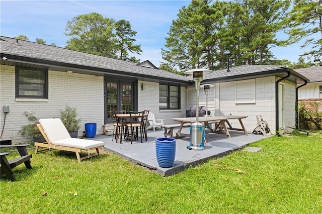 back of property with a yard and a patio