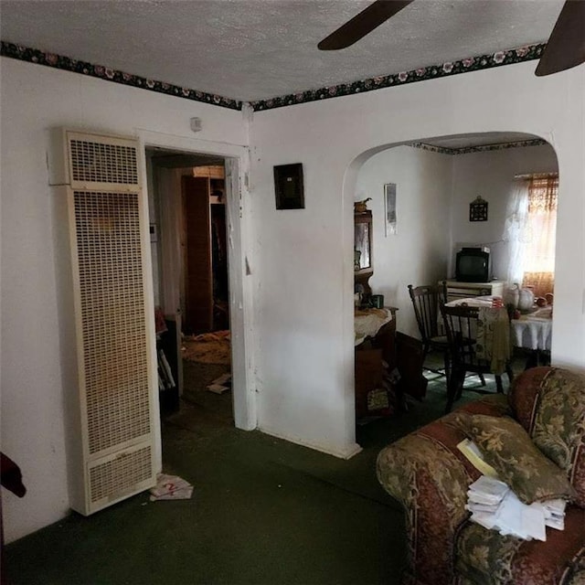 bedroom featuring ceiling fan, arched walkways, a textured ceiling, and a heating unit