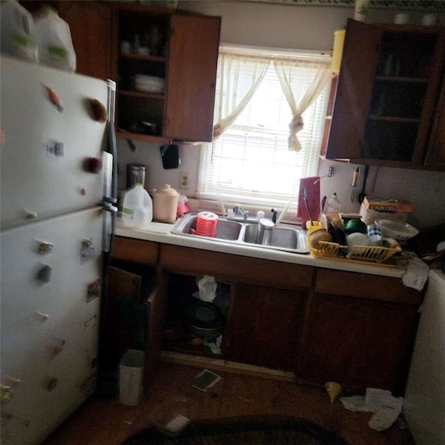 kitchen featuring a sink, open shelves, light countertops, and freestanding refrigerator