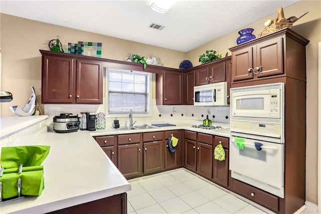 kitchen with light tile patterned flooring, decorative backsplash, sink, and white appliances