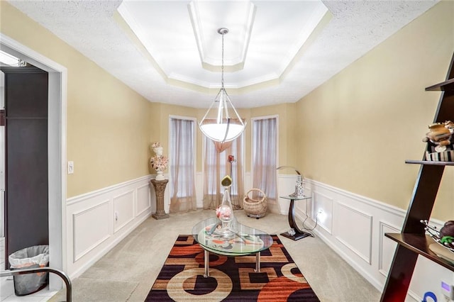 carpeted dining area with crown molding, a tray ceiling, and a textured ceiling