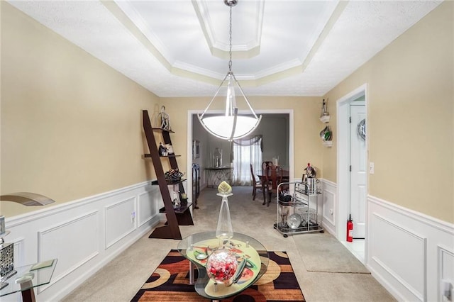 carpeted dining space with crown molding and a raised ceiling