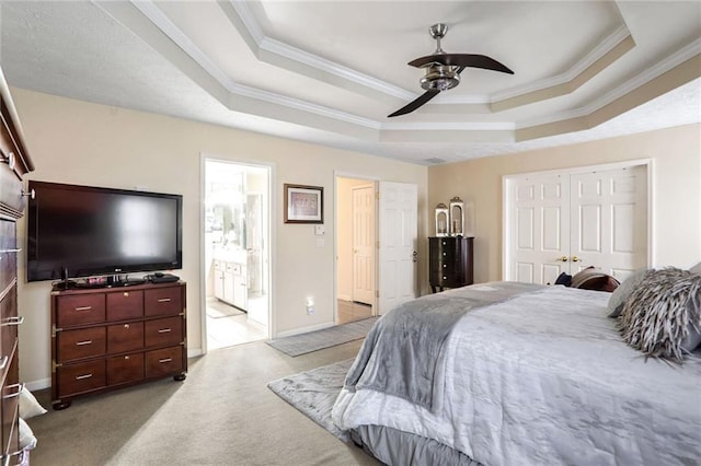 bedroom with ceiling fan, ensuite bathroom, and a raised ceiling