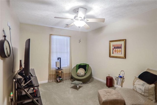 living area with light carpet, ceiling fan, and a textured ceiling