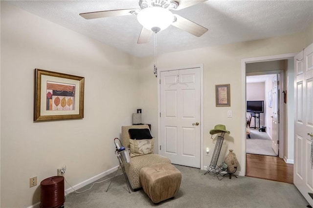 sitting room with ceiling fan, a textured ceiling, and light carpet