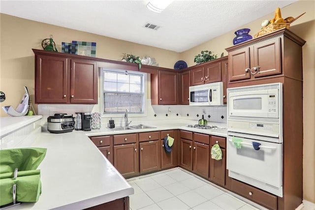 kitchen with tasteful backsplash, kitchen peninsula, sink, white appliances, and light tile patterned flooring