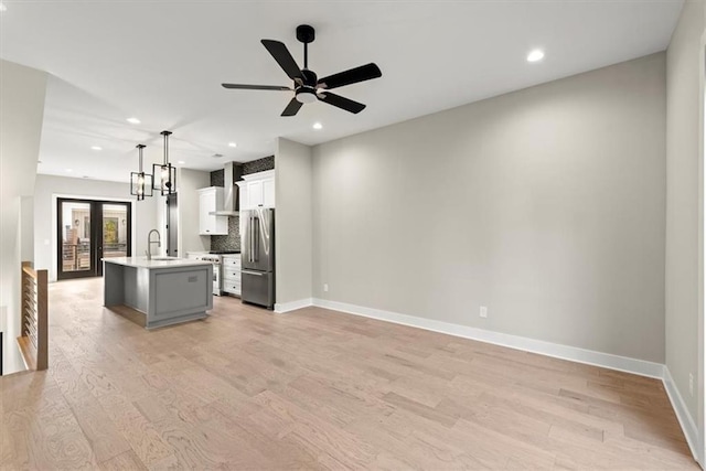 kitchen featuring sink, hanging light fixtures, light hardwood / wood-style floors, a kitchen island with sink, and appliances with stainless steel finishes