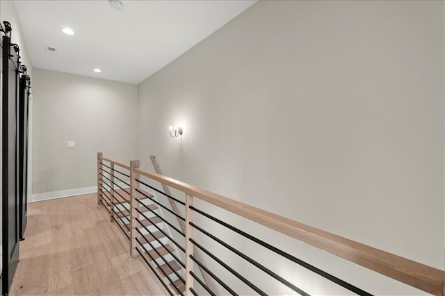 hallway featuring light wood-type flooring and a barn door