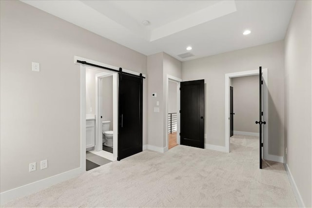 carpeted bedroom featuring connected bathroom and a barn door