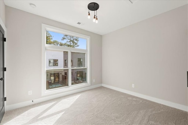 carpeted spare room featuring a chandelier