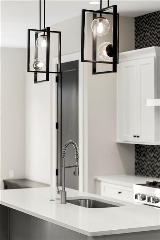 kitchen with backsplash, decorative light fixtures, white cabinetry, and sink