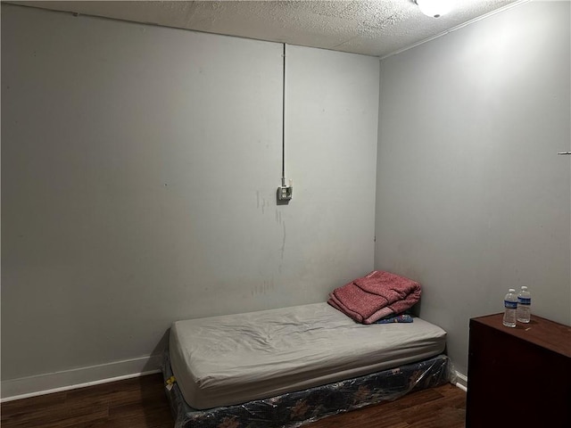 bedroom featuring a textured ceiling and dark hardwood / wood-style flooring