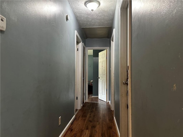 hallway featuring a textured ceiling and dark hardwood / wood-style floors