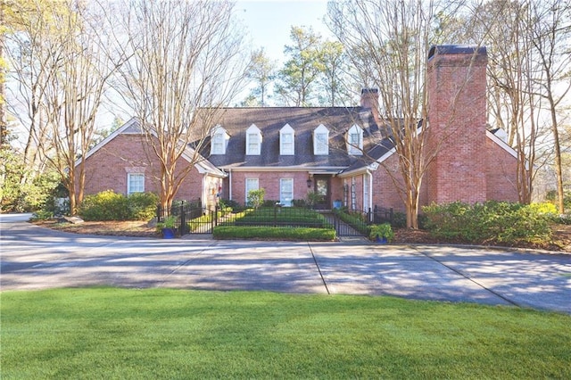 new england style home with a front lawn, brick siding, a fenced front yard, and a chimney