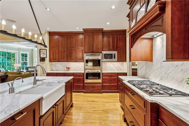 kitchen with light wood finished floors, tasteful backsplash, dark brown cabinets, appliances with stainless steel finishes, and a sink