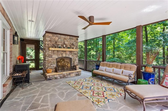 sunroom / solarium with a fireplace, wooden ceiling, a wood stove, and a ceiling fan