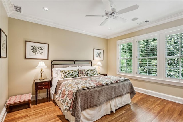 bedroom with visible vents, wood finished floors, baseboards, and ornamental molding