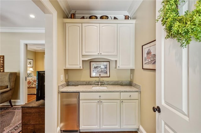 kitchen featuring crown molding, light stone counters, stainless steel fridge, and a sink