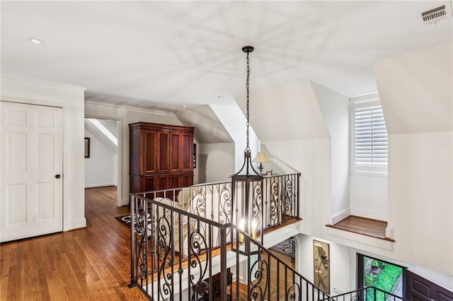 hallway featuring wood finished floors, an upstairs landing, visible vents, and lofted ceiling