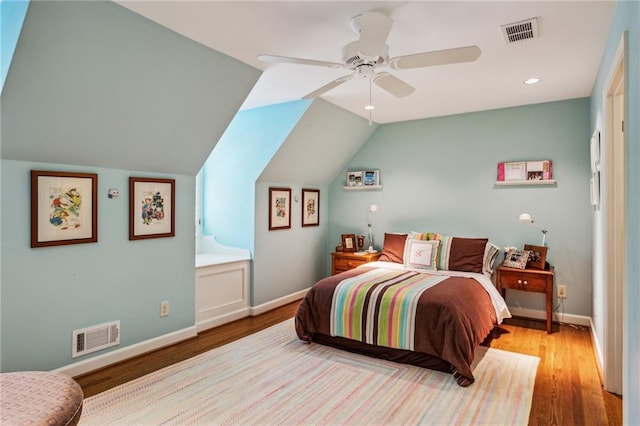 bedroom with lofted ceiling, wood finished floors, visible vents, and baseboards