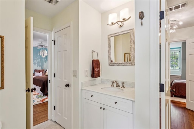 ensuite bathroom with vanity, wood finished floors, visible vents, and connected bathroom