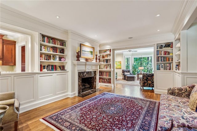 living room with a premium fireplace, wood finished floors, and crown molding