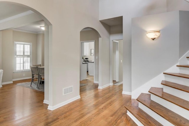 entrance foyer with ornamental molding and light hardwood / wood-style floors