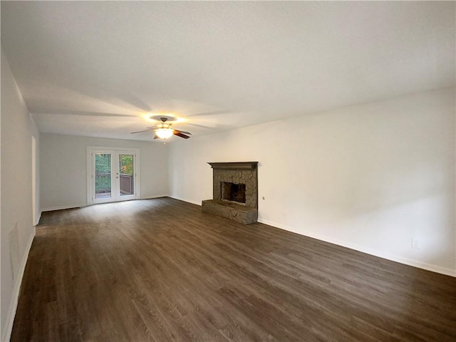 unfurnished living room featuring a fireplace, french doors, dark hardwood / wood-style floors, and ceiling fan