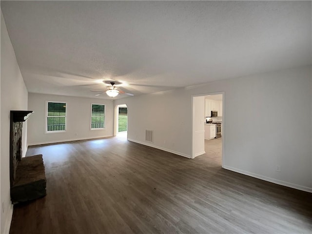 unfurnished living room featuring a textured ceiling, ceiling fan, dark hardwood / wood-style flooring, and a fireplace