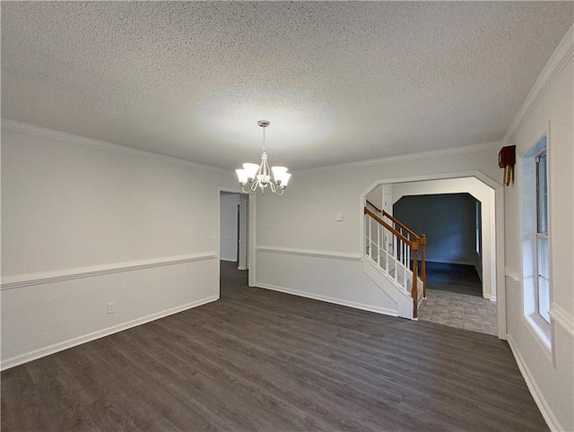 empty room with crown molding, dark hardwood / wood-style flooring, a textured ceiling, and an inviting chandelier