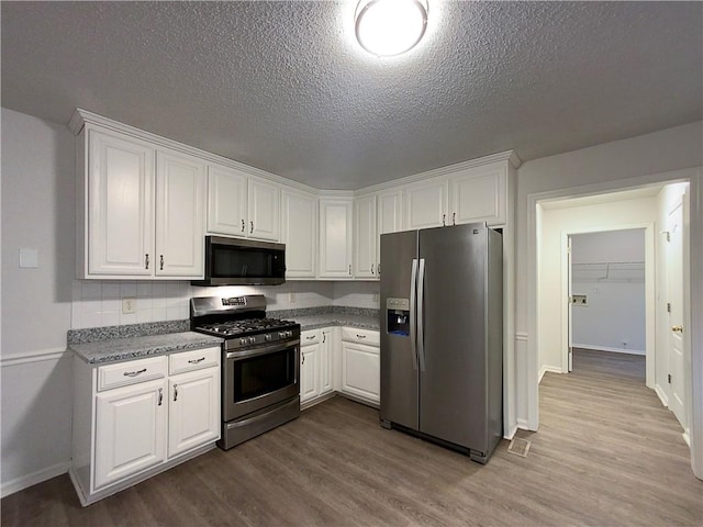 kitchen with white cabinets, light wood-type flooring, a textured ceiling, and appliances with stainless steel finishes