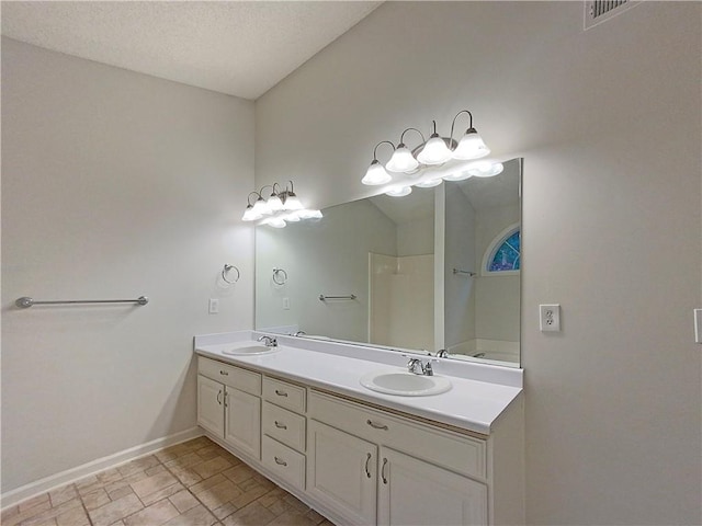 bathroom featuring vanity, a textured ceiling, and walk in shower