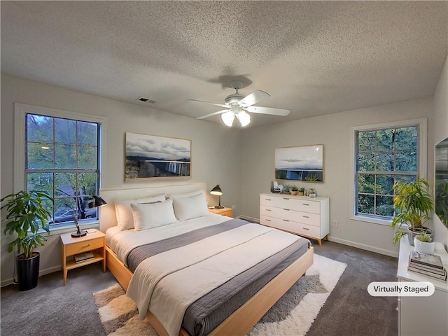 carpeted bedroom with ceiling fan, a textured ceiling, and multiple windows