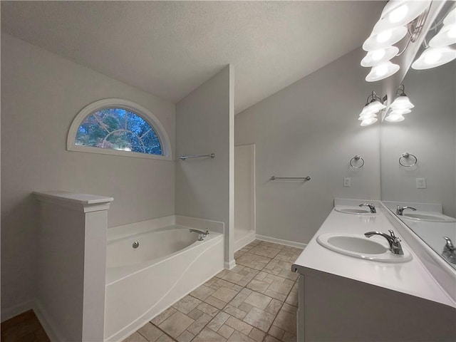 bathroom featuring a textured ceiling, vanity, a tub, and vaulted ceiling