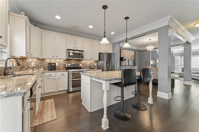 kitchen featuring sink, white cabinetry, appliances with stainless steel finishes, a kitchen island, and pendant lighting