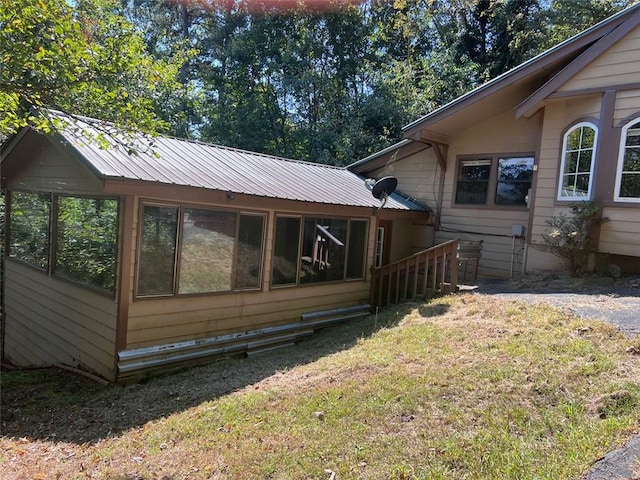 view of side of property featuring a sunroom and a lawn