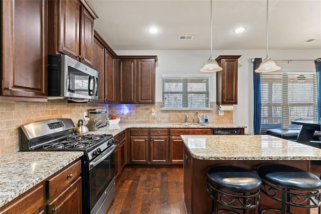 kitchen with pendant lighting, sink, a kitchen breakfast bar, decorative backsplash, and stainless steel appliances