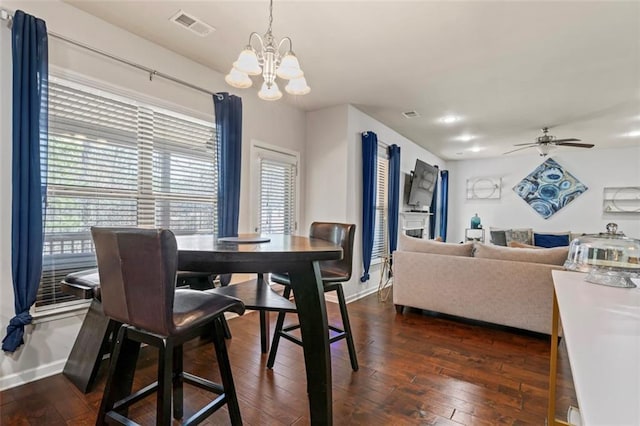 dining space featuring dark hardwood / wood-style floors and ceiling fan with notable chandelier