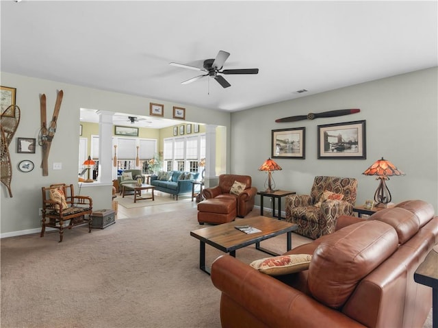 carpeted living room with visible vents, baseboards, decorative columns, and a ceiling fan