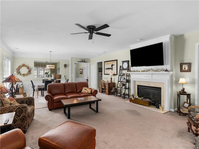 living area with crown molding, carpet flooring, a high end fireplace, and a ceiling fan