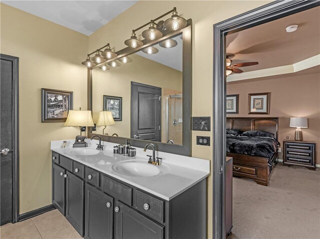 ensuite bathroom with double vanity, tile patterned flooring, a ceiling fan, and a sink