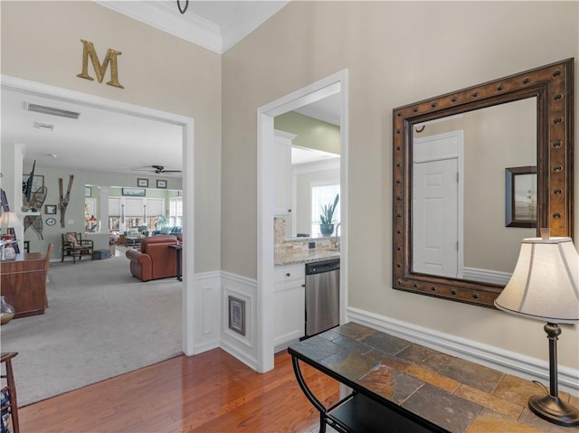 foyer featuring visible vents, a ceiling fan, wainscoting, ornamental molding, and wood finished floors