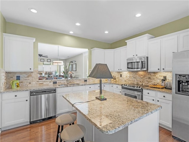 kitchen with stainless steel appliances, a sink, a center island, and white cabinets