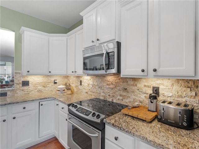 kitchen with light stone countertops, tasteful backsplash, appliances with stainless steel finishes, and white cabinets