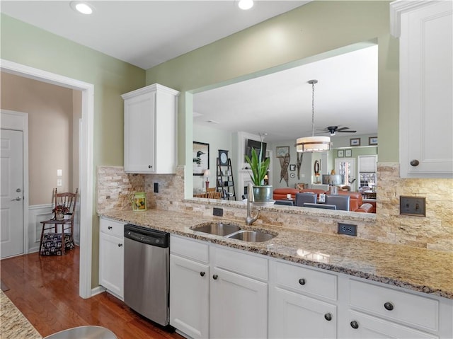 kitchen featuring white cabinets, dishwasher, light stone counters, dark wood-type flooring, and a sink