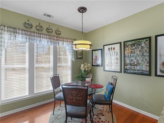 dining area with wood finished floors, visible vents, and baseboards